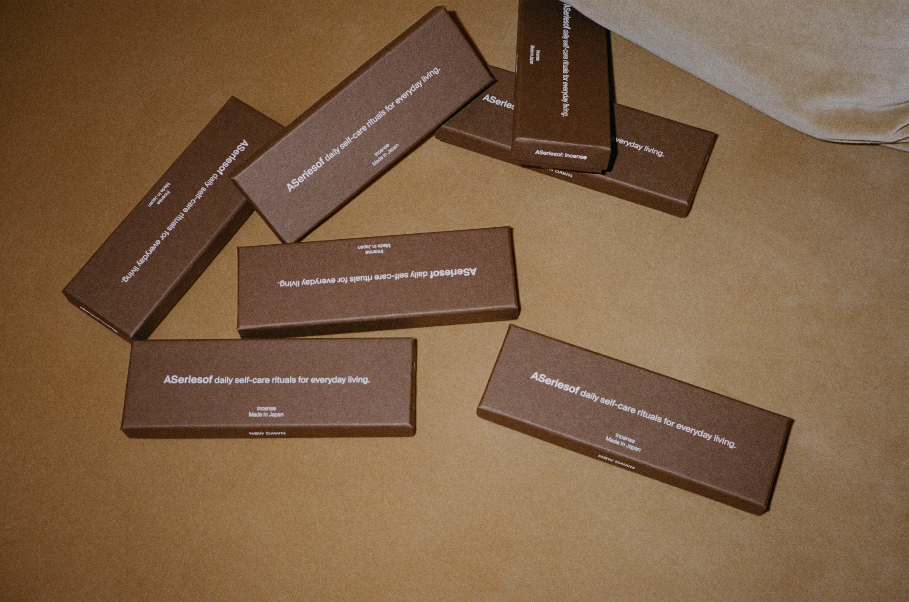 Japanese incense sticks brown boxes made in Japan saying "a series of daily self-care rituals for everyday living." on a couch in a luxury hotel.