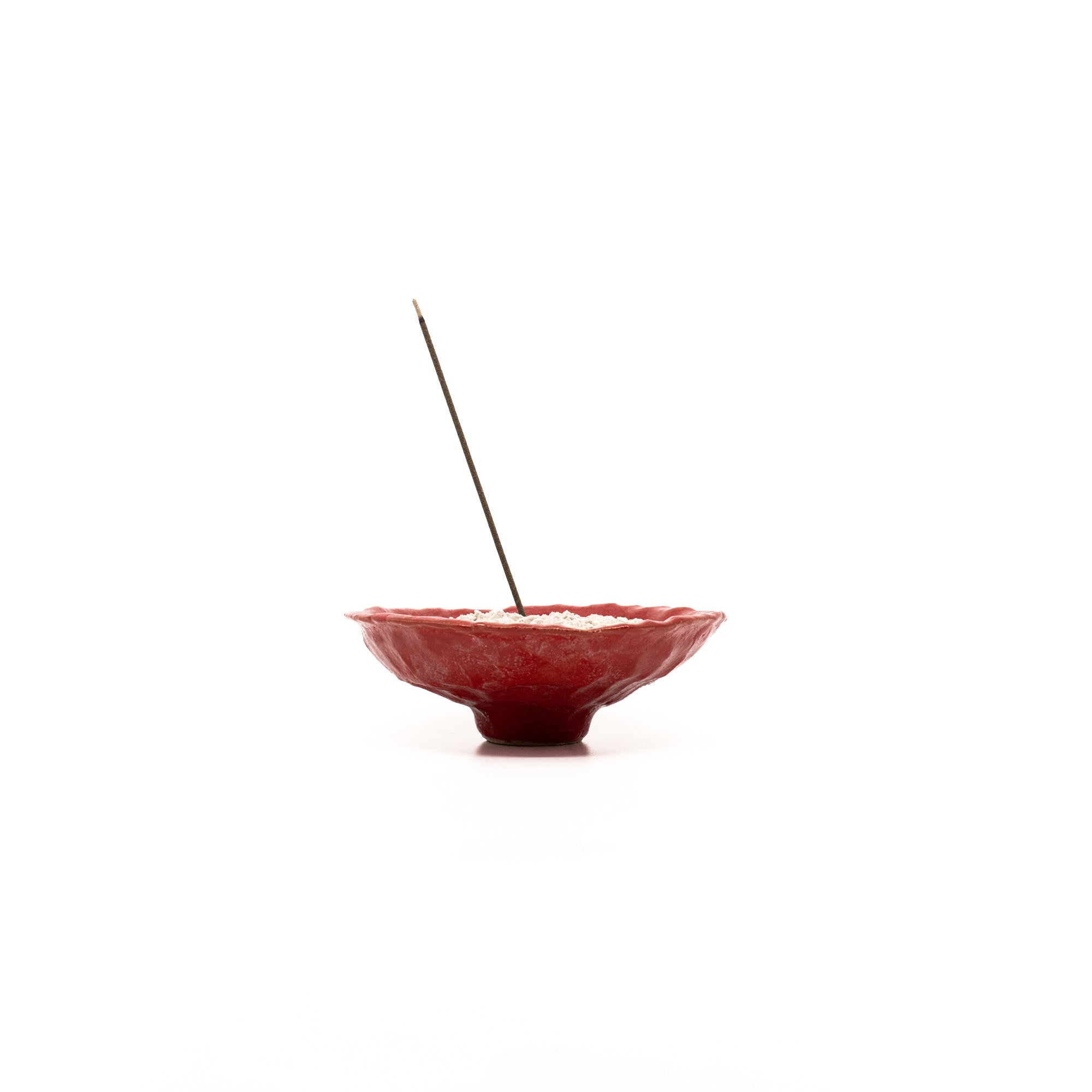 ASeriesof incense stick bamboo-less and made in Japan, burning in a red ceramic vase filled with traditional Japanese ashes.