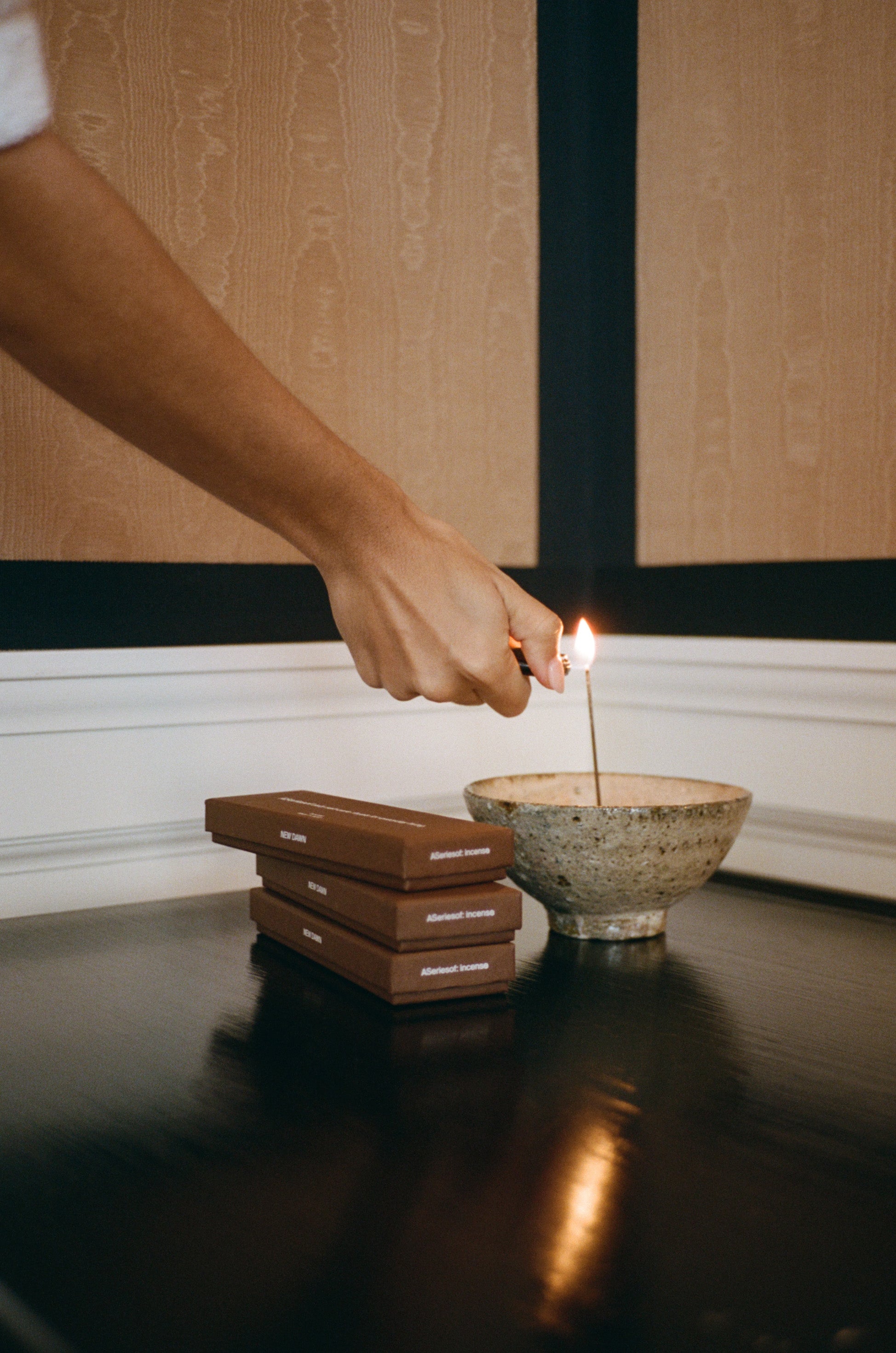 how to light incense: Japanese Incense sticks burning in a incense holder next to a stack of incense boxes made in Japan in a luxury hotel. 